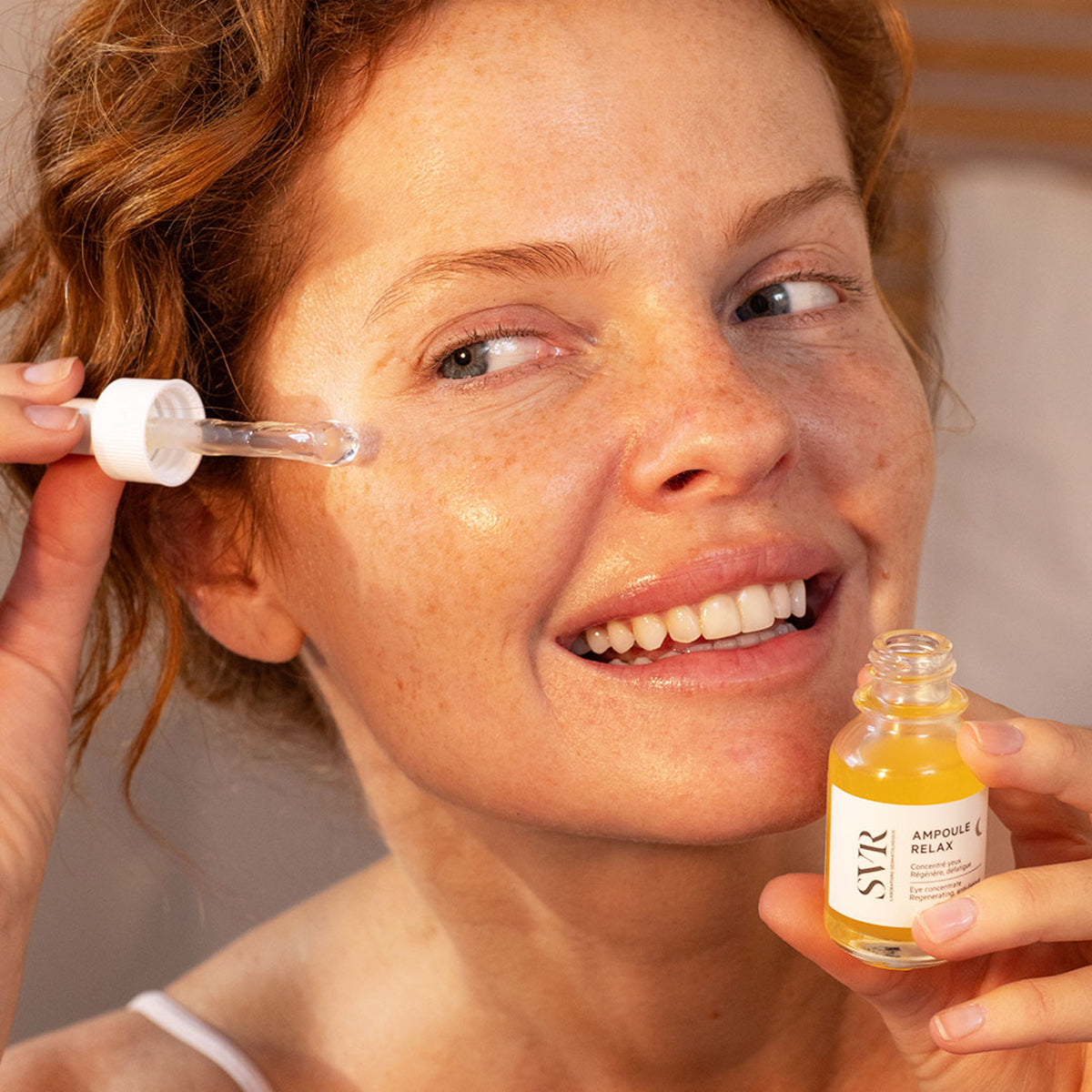 Frau trägt SVR Ampoule Relax Augenkonzentrat mit metallischer Pipette auf die empfindliche Augenpartie auf.
