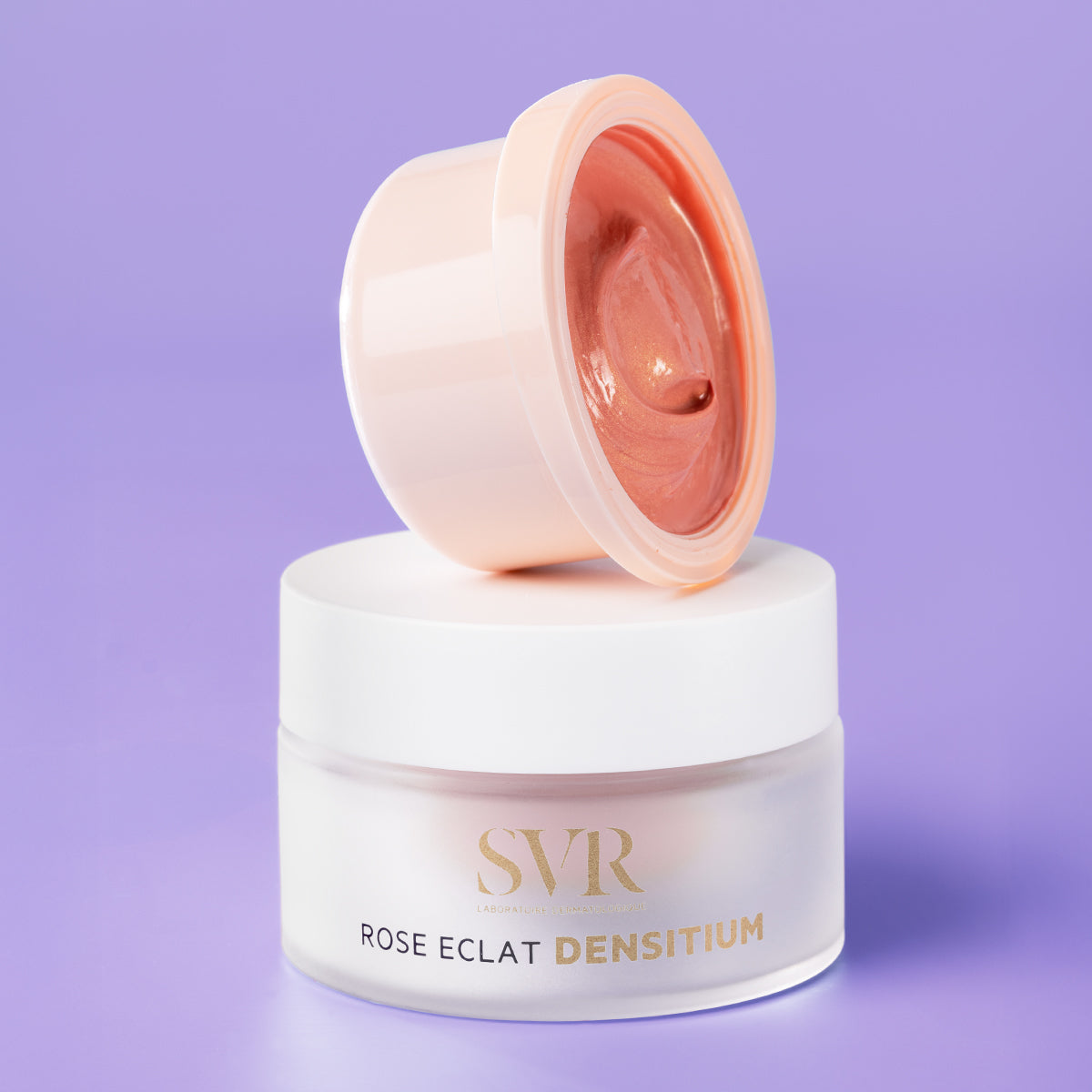 SVR Densitium Rose Éclat refill pod resting on a frosted glass jar against a soft purple background.