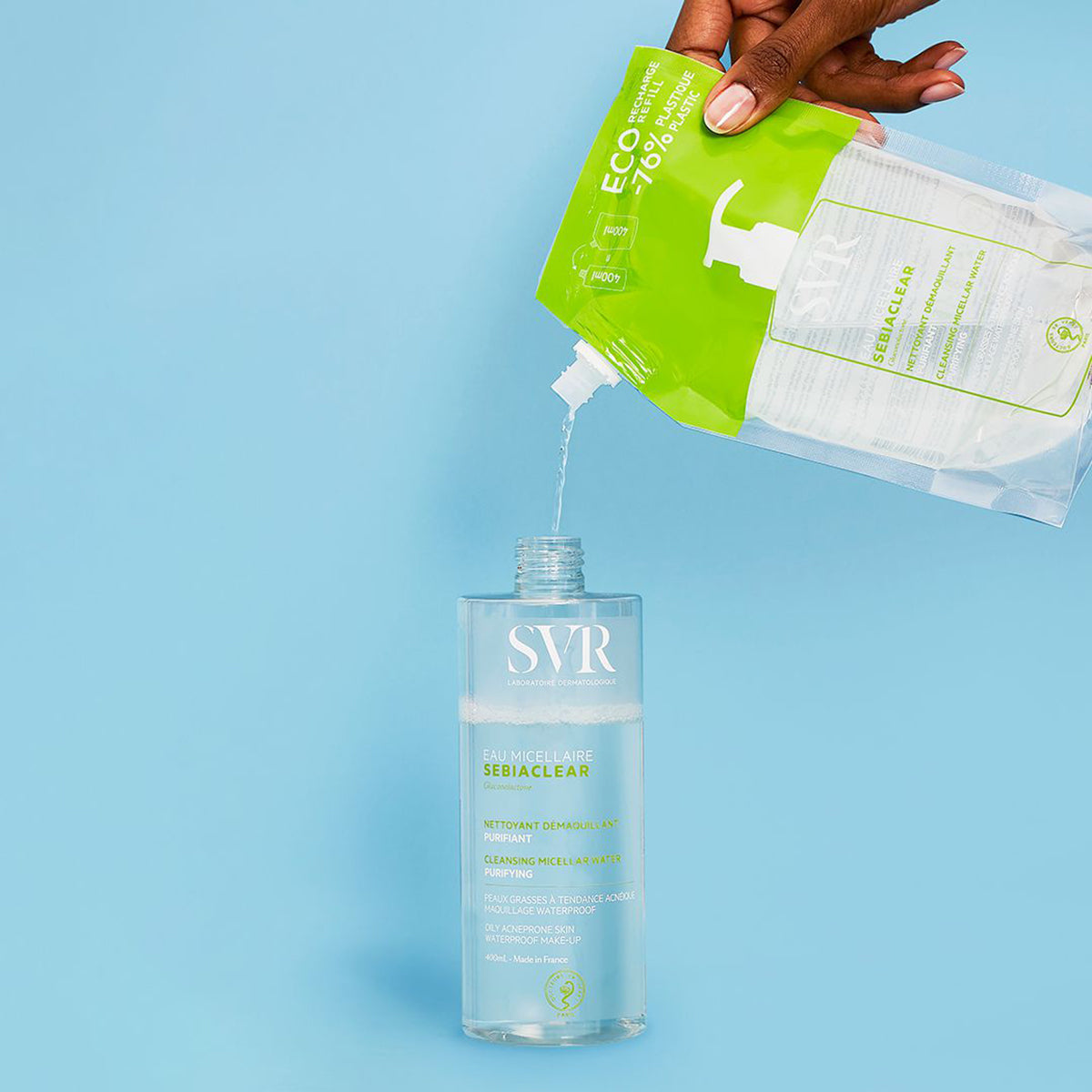 SVR Sebiaclear Mizellenwasser Nachfüllbeutel wird in eine transparente 400ml Flasche auf hellblauem Hintergrund gegossen.