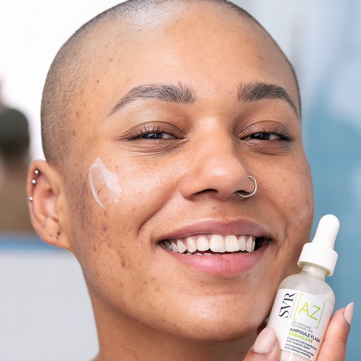 Lächelnde Person mit SVR Sebiaclear Ampoule Flash Serum gegen Unreinheiten auf der Wange.