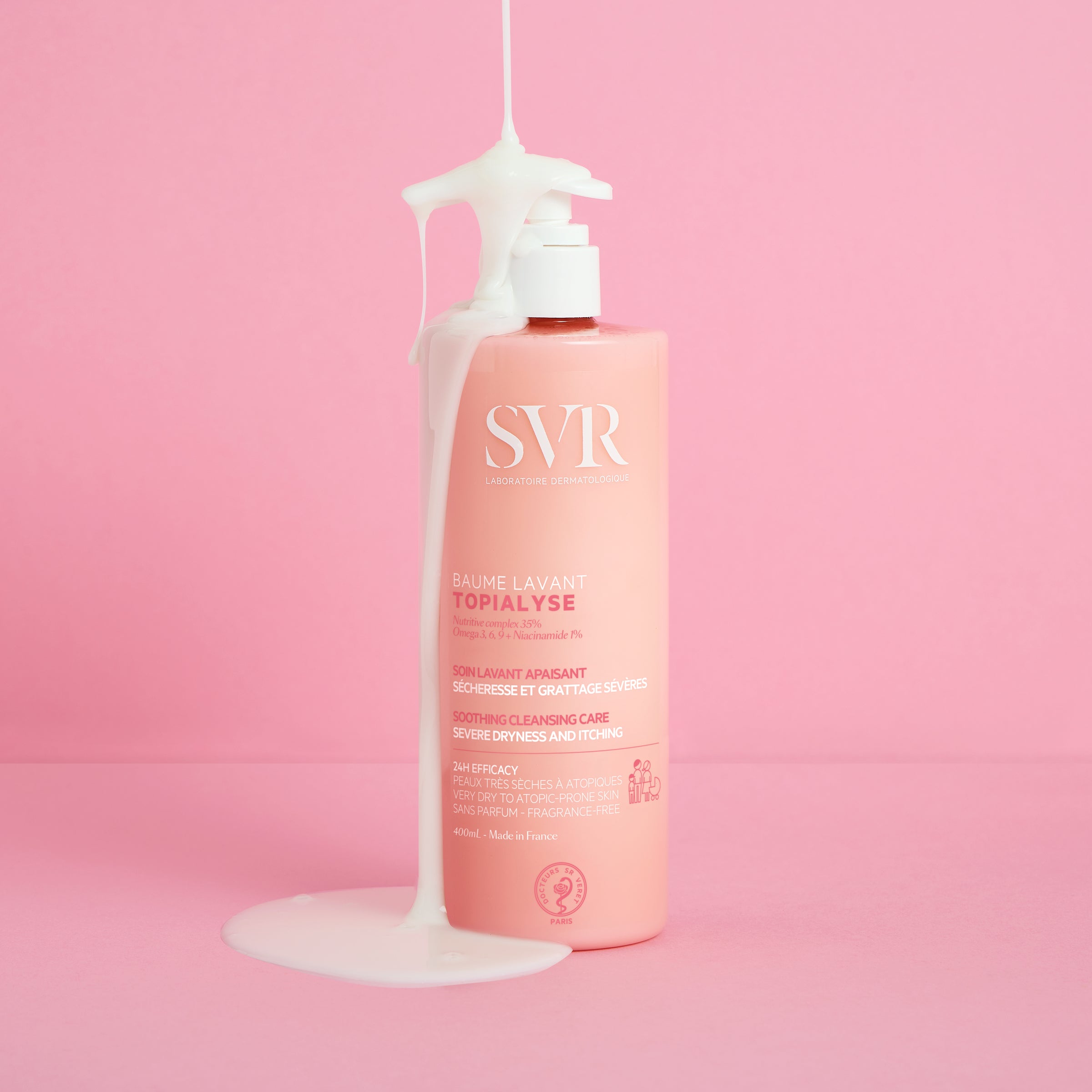 Rosa 400ml SVR Topialyse Baume Lavant Flasche mit weißem Pumpspender und herablaufender cremiger Textur auf rosa Hintergrund.