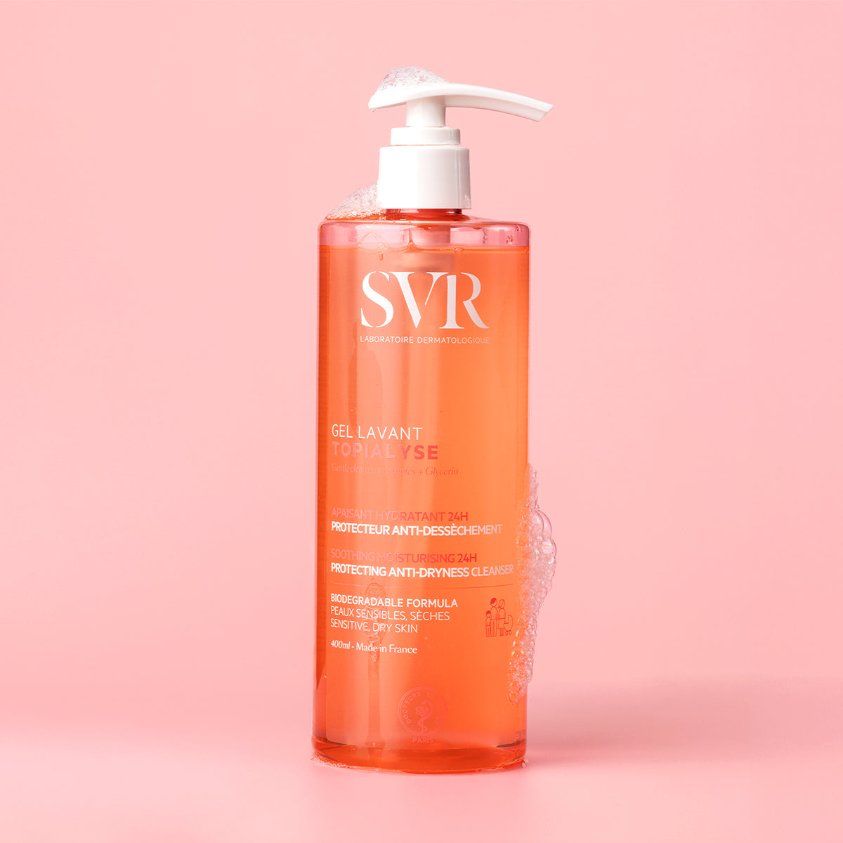 Transparente 400ml-Flasche SVR Topialyse Gel Lavant mit weißem Pumpspender und Schaum auf einem zartrosa Hintergrund.