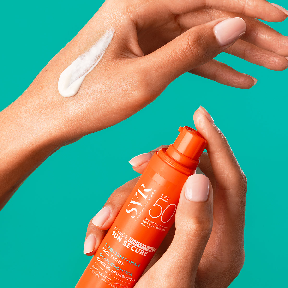 SVR Sun Secure Photo-Age SPF50+ Fluid in einer orangefarbenen Pumpflasche, aufgetragen als weiße Creme auf dem Handrücken.