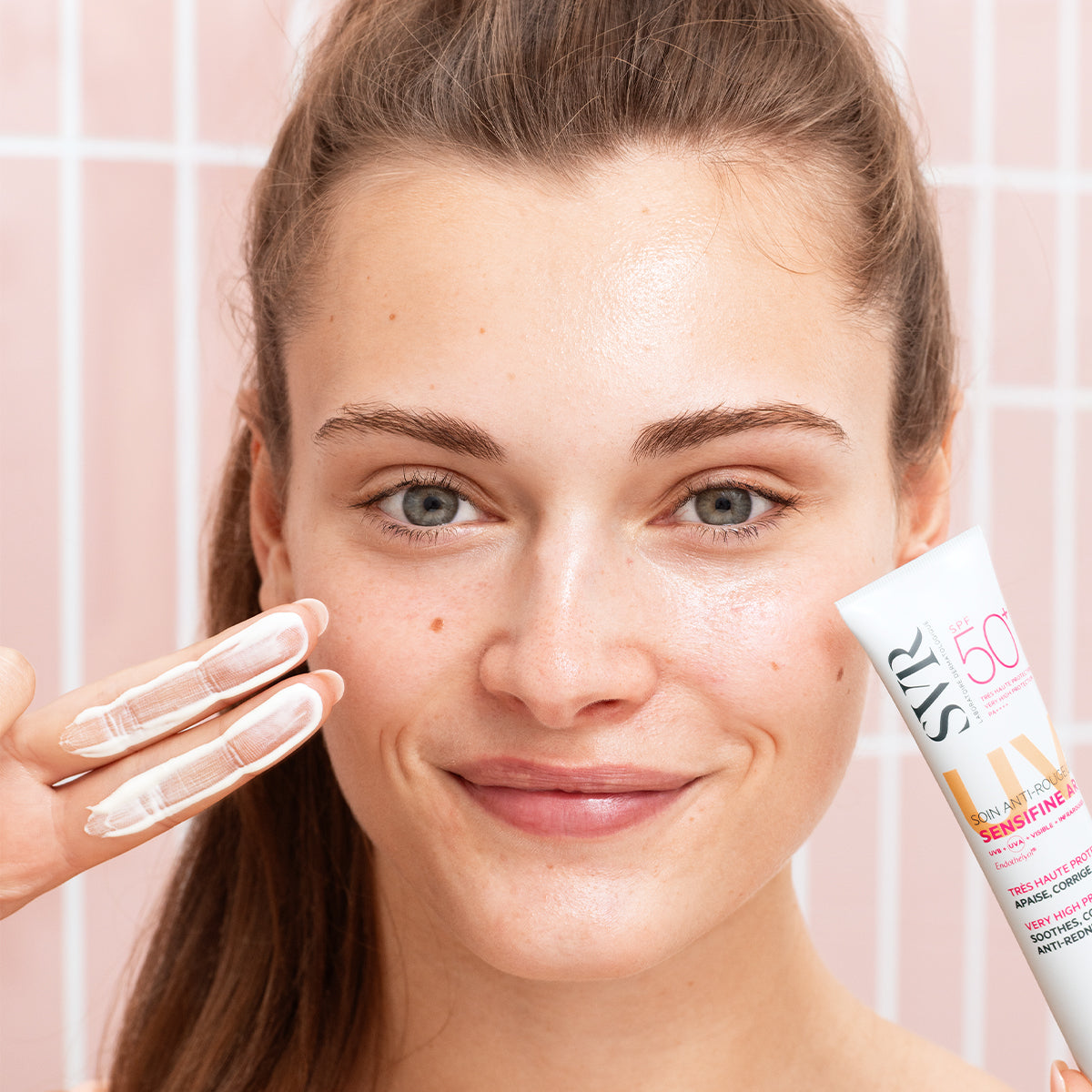 Frau trägt SVR Sensifine AR Crème SPF50+ auf ihr Gesicht auf, um Rötungen zu lindern und die Haut vor der Sonne zu schützen.