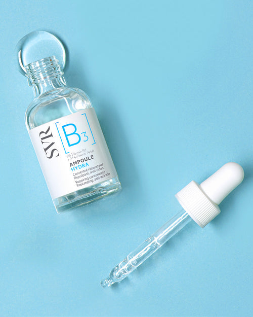 SVR B3 Ampoule Hydra Serum in einer Glasflasche mit Pipette auf hellblauem Hintergrund.