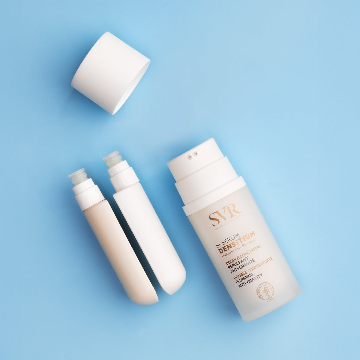 SVR Densitium Bi-Sérum dual-chamber pump bottle with white cap and two separate serum refills on a blue background.