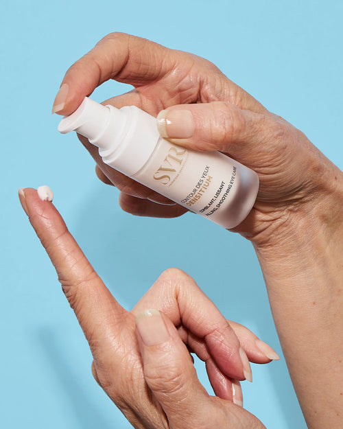 Hände halten einen weißen SVR DENSITIUM Augencreme-Spender und tragen eine kleine Menge Creme auf den Finger auf.