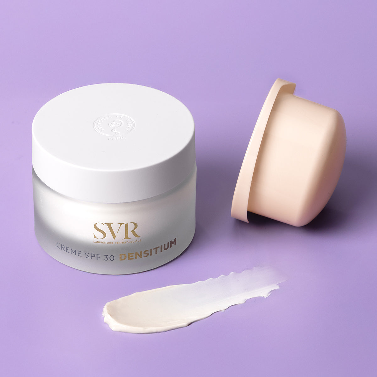 SVR Densitium Crème SPF30 in a frosted glass jar with a white lid, open cap, and a creamy white product swatch on purple.