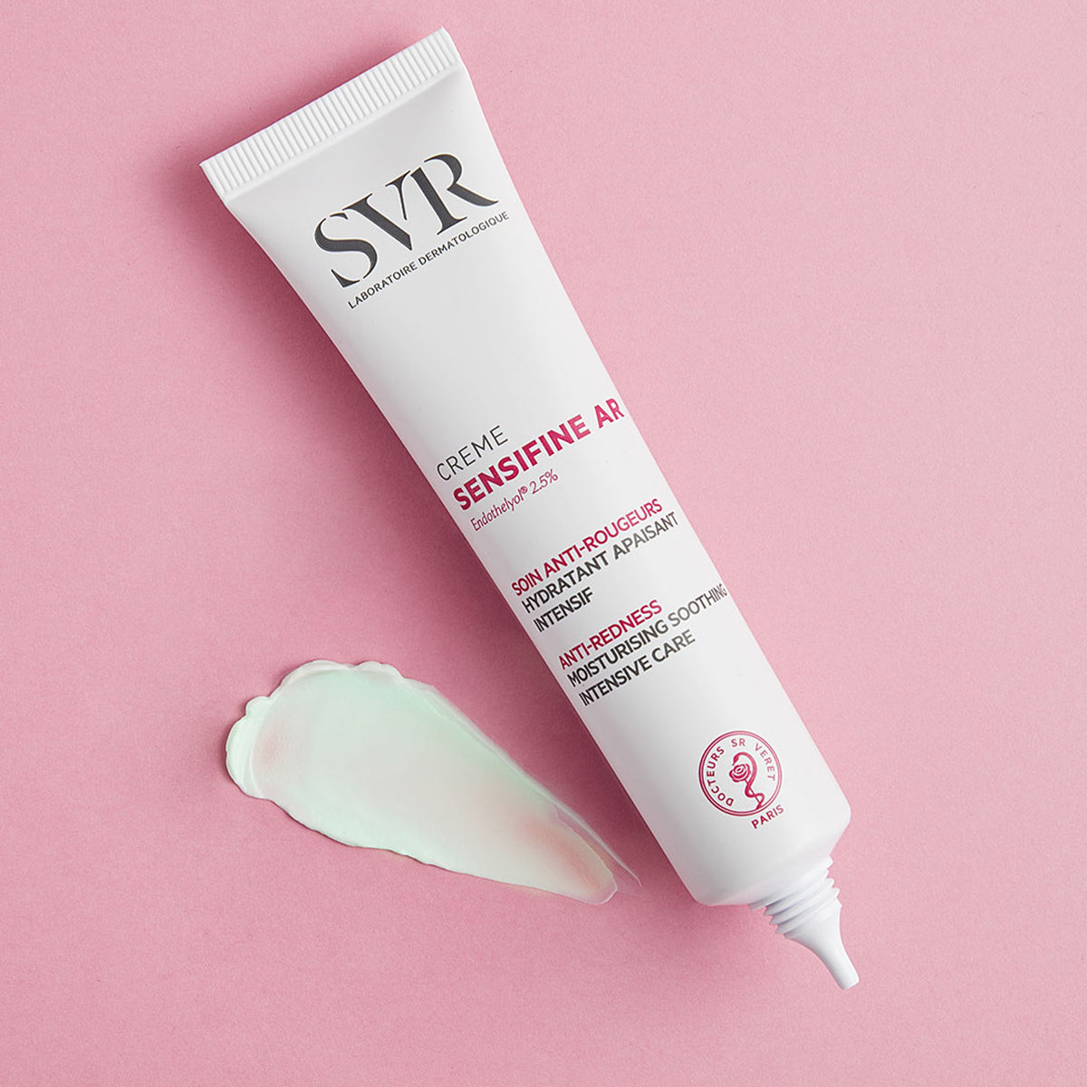 Weiße SVR Sensifine AR Creme Tube mit einem Klecks hellgrüner, beruhigender Gel-Creme auf einem zartrosa Hintergrund.