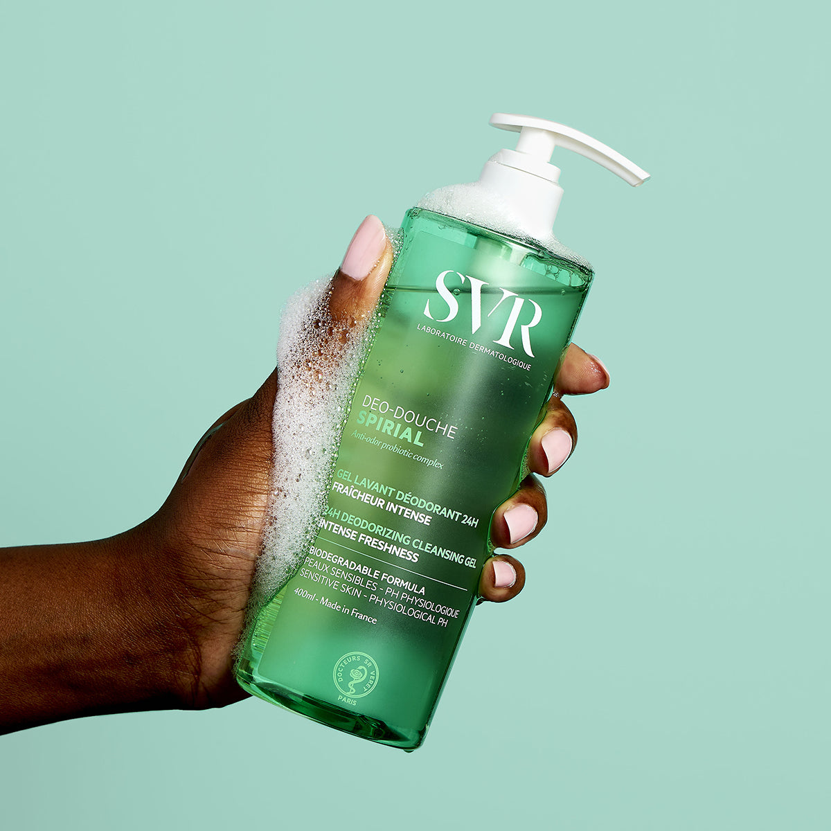 Hand hält eine grüne 400ml SVR Spirial Deo-Douche Pumpflasche mit weißem Schaum vor hellgrünem Hintergrund.