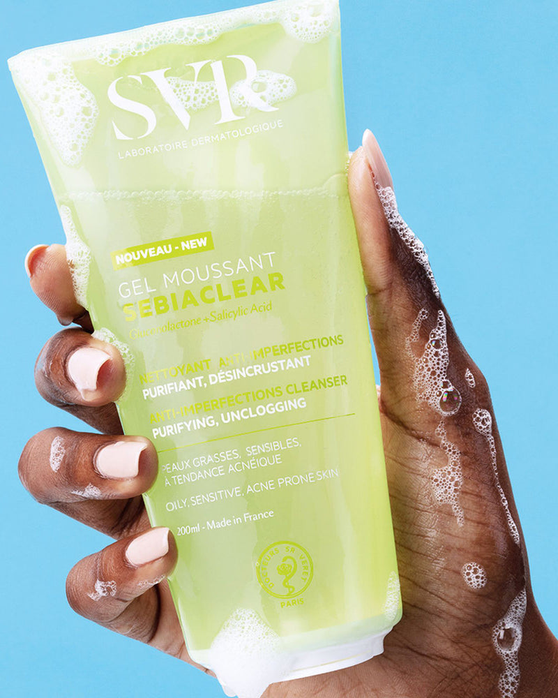 SVR SEBIACLEAR Gel Moussant 200ml Tube in einer Hand mit Schaum vor hellblauem Hintergrund.