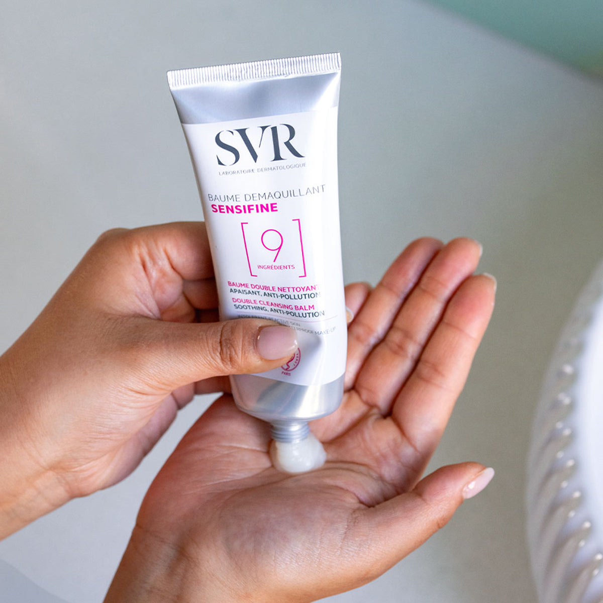 SVR SENSIFINE Reinigungsbalsam in silberner Tube, der eine cremige Textur auf die Handfläche abgibt.