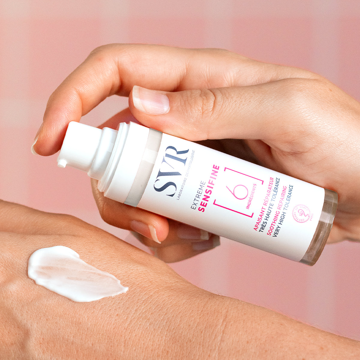 SVR Sensifine Extreme soothing repair cream in a white pump bottle being applied to a hand as a white lotion.