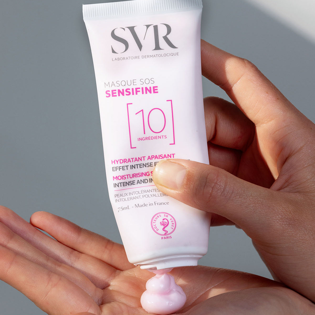 SVR Sensifine Masque SOS Tube in der Hand mit einer Portion rosa Gesichtsmaske auf der Handfläche.