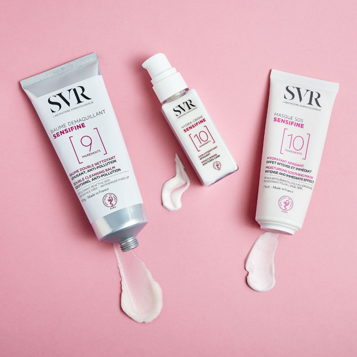 SVR Sensifine Hautpflege-Set mit Reinigungsbalsam, Creme und SOS-Maske in weißen Tuben auf rosa Hintergrund.