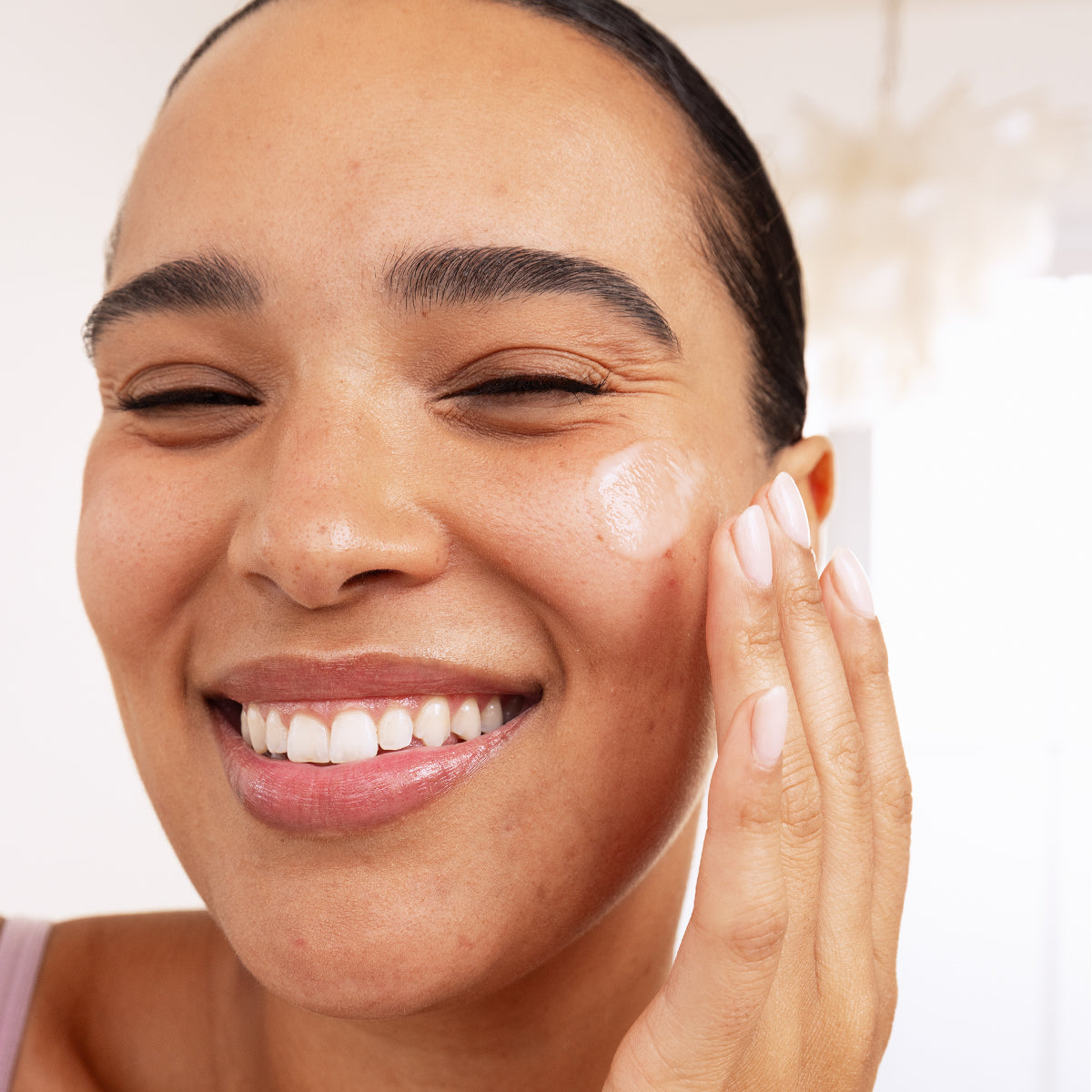 Lächelnde Frau trägt das transparente SEBIACLEAR Serum auf ihre Wange auf, um Hautunreinheiten sanft zu pflegen.