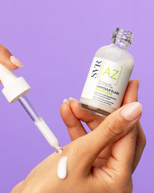 SVR Sebiaclear Ampoule Flash Fläschchen mit Pipette und milchigem Serum auf der Hand vor lila Hintergrund.
