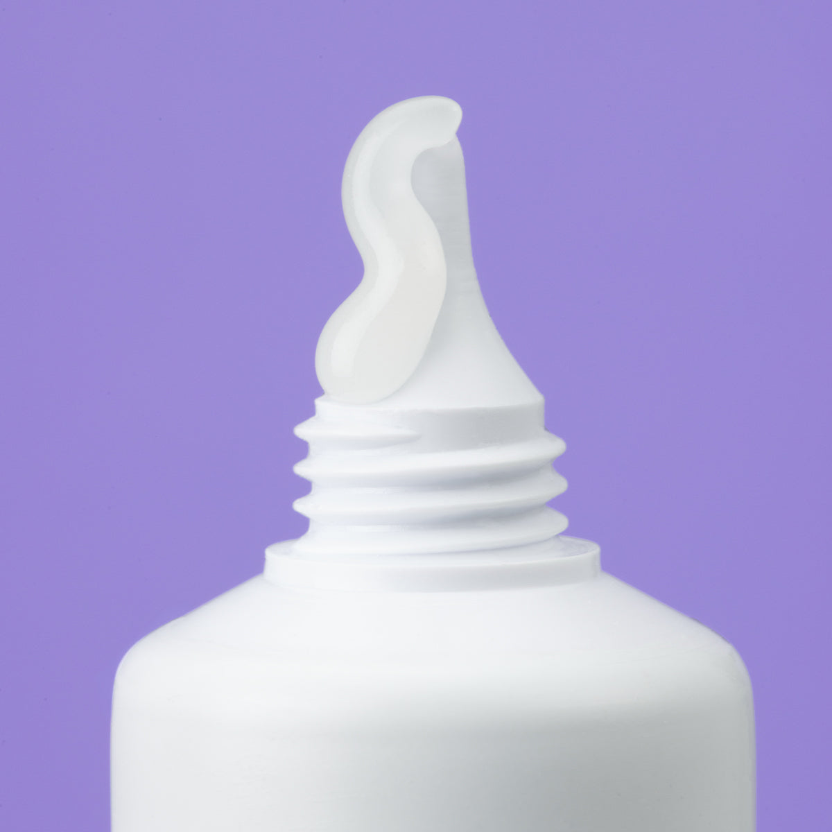 Clear gel squeezed from a white plastic tube nozzle against a solid purple background.