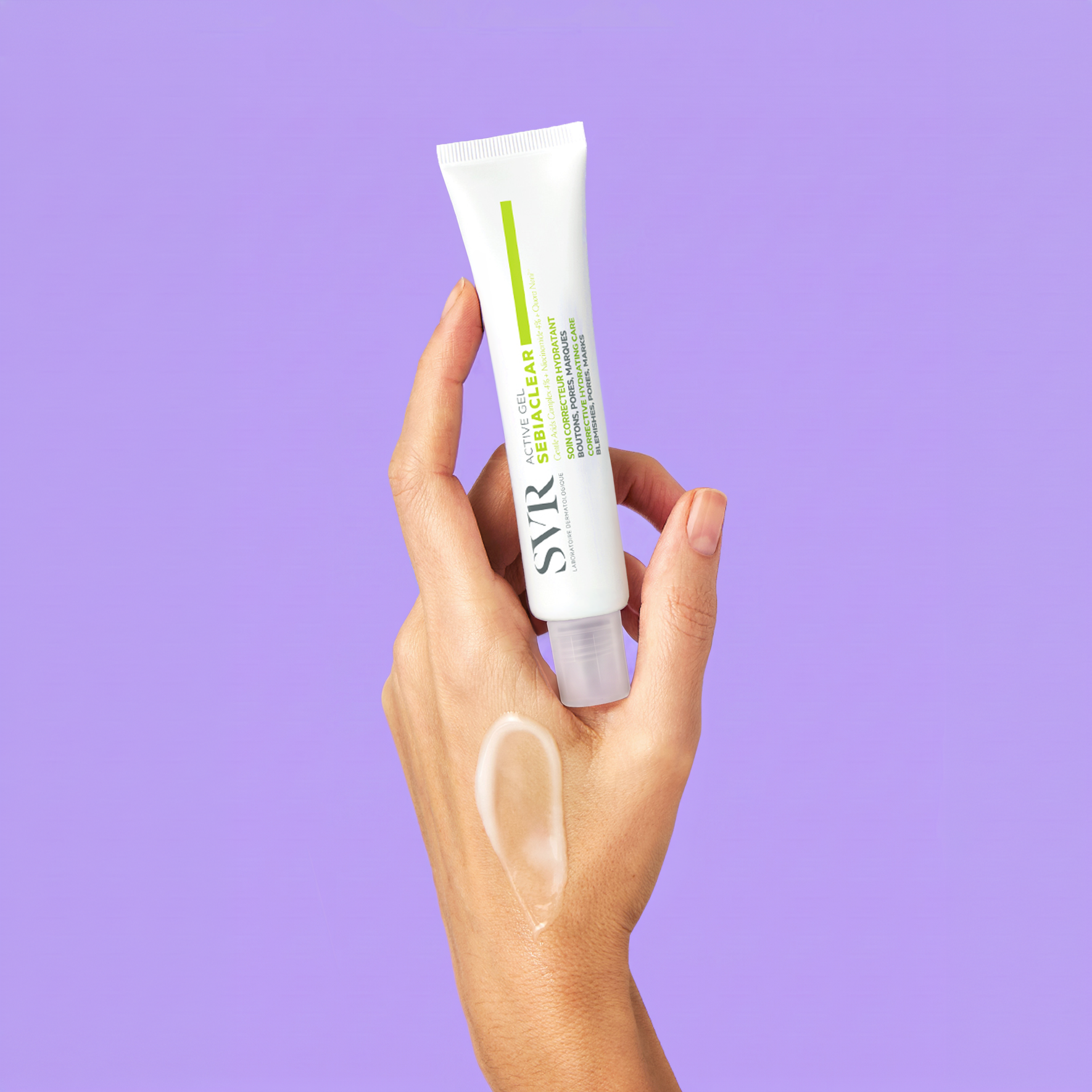 Hand hält weiße SVR Sebiaclear Active Gel Tube mit grünem Akzent vor fliederfarbenem Hintergrund.